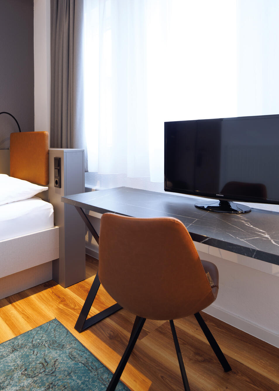 Single room with bed, desk, chair and screen in the International Student Hotel