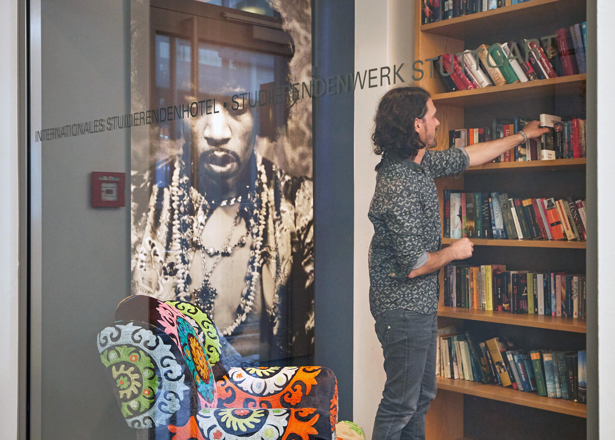 Ein Mann nimmt in der Leseecke des Internationalen Studierendenhotel ein Buch aus dem Regal