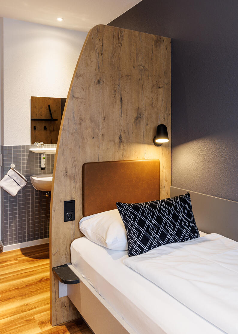 Single room with bed, wardrobe and washbasin in the International Student Hotel