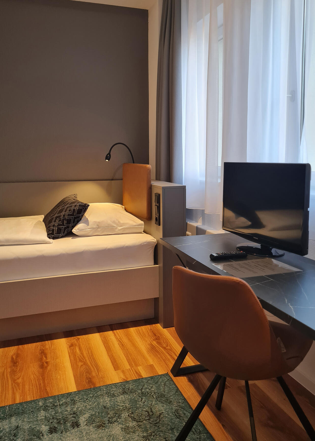 Single room with bed, desk, chair and screen in the International Student Hotel