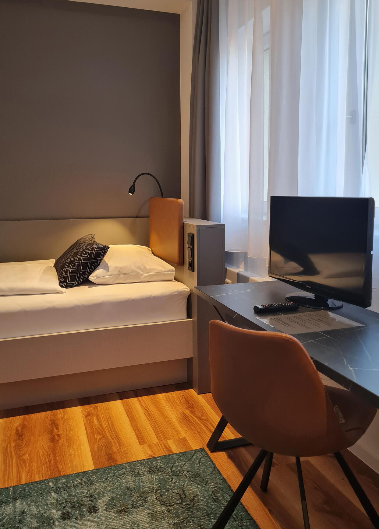 Einzelzimmer mit Bett, Schreibtisch, Stuhl und Bildschirm im Internationalen Studierendenhotel